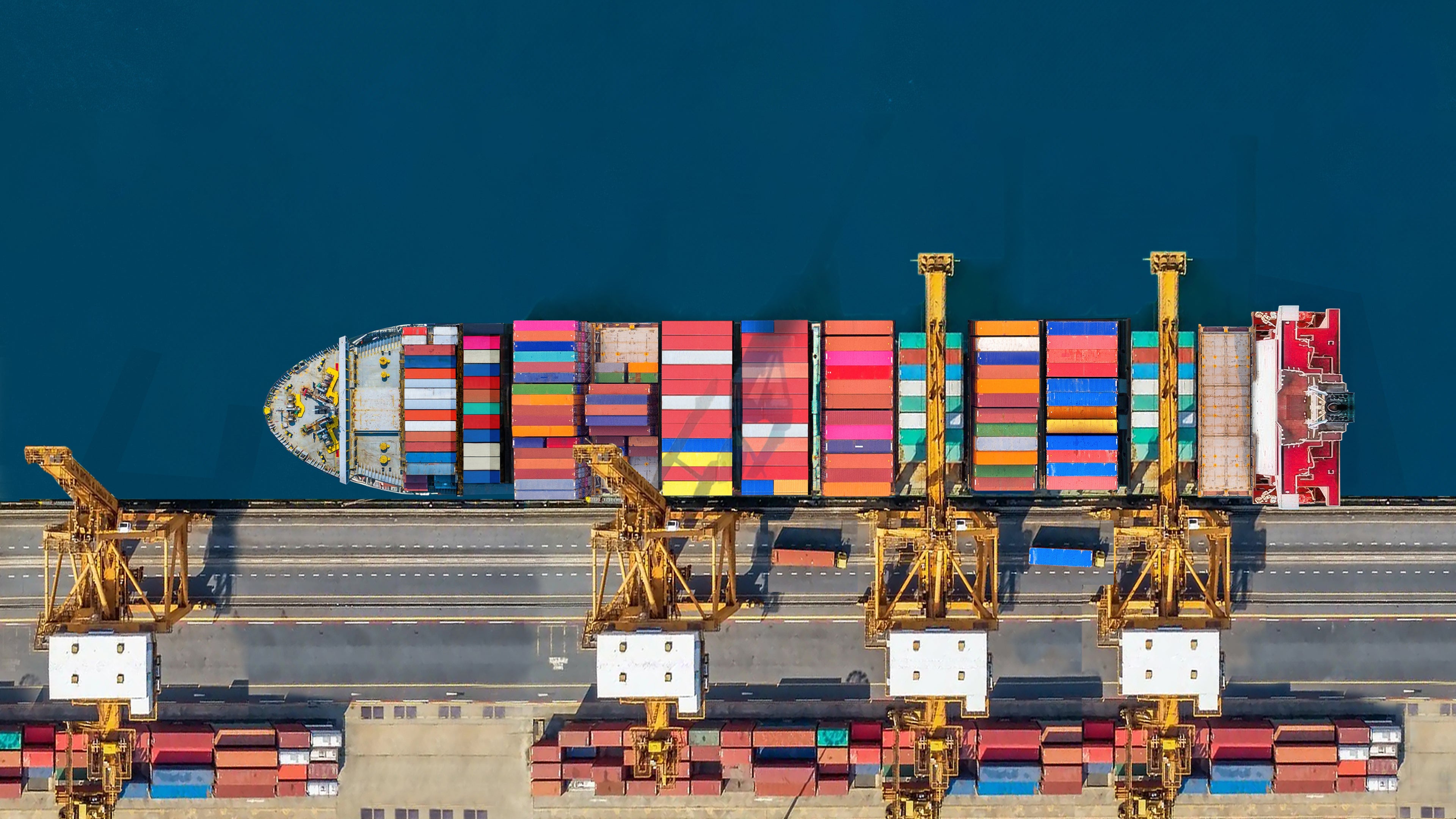 Aerial top view of a container ship in port, with cranes loading and off-loading containers.