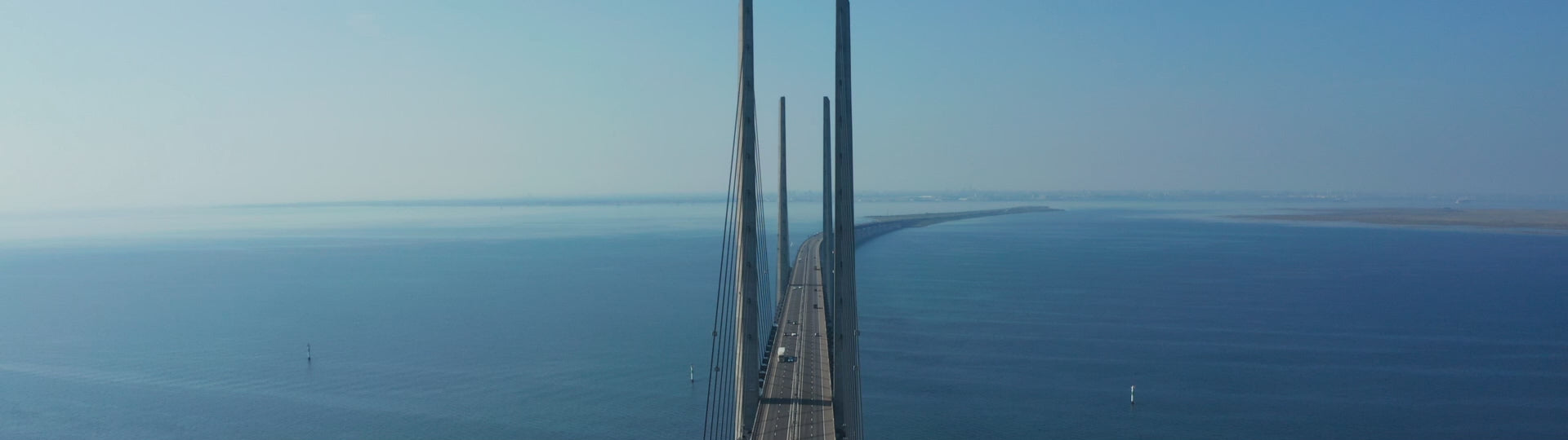 Aerial drone fly-by video of the Öresund bridge connecting Malmö in Sweden with Copenhagen in Denmark, on a sunny summer day.
